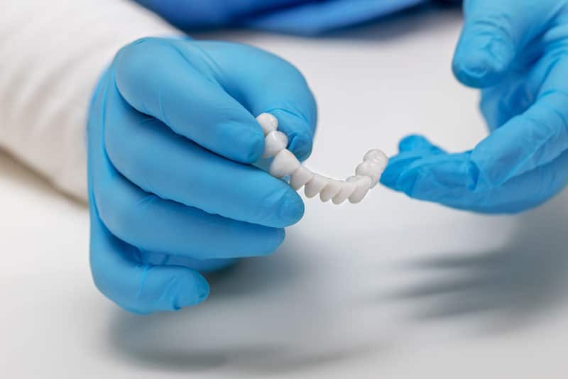 a dental professional working on a full arch dental implant model.